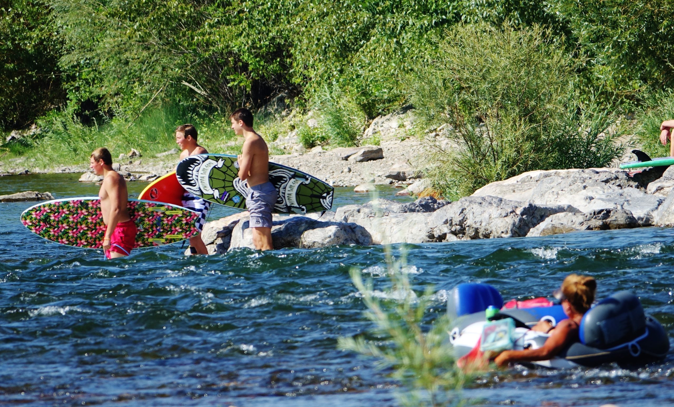 People float and paddle the river in summer